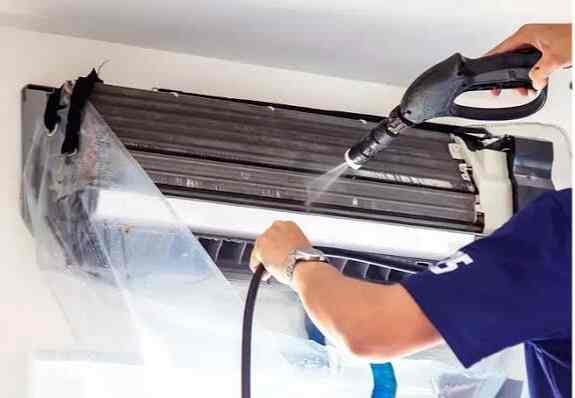 AC service technician performing maintenance on split AC in Lahore