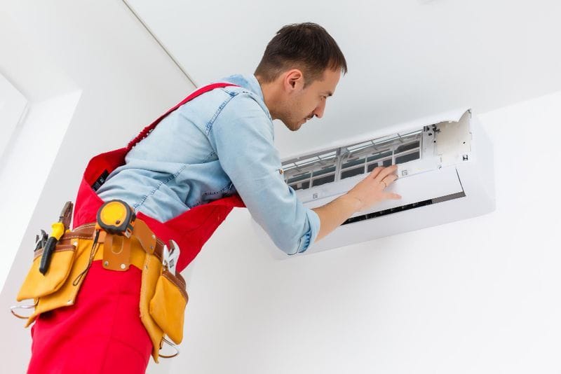 AC service technician cleaning a split unit in Lahore